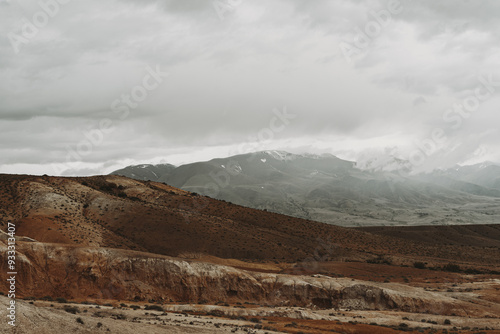 A breathtaking landscape showcasing the rugged Altai Mountains with clouds overhead, highlighting the natural beauty of early autumn