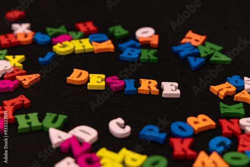 Fényképezés The word DESIRE is displayed in painted wooden letters with various colors, se