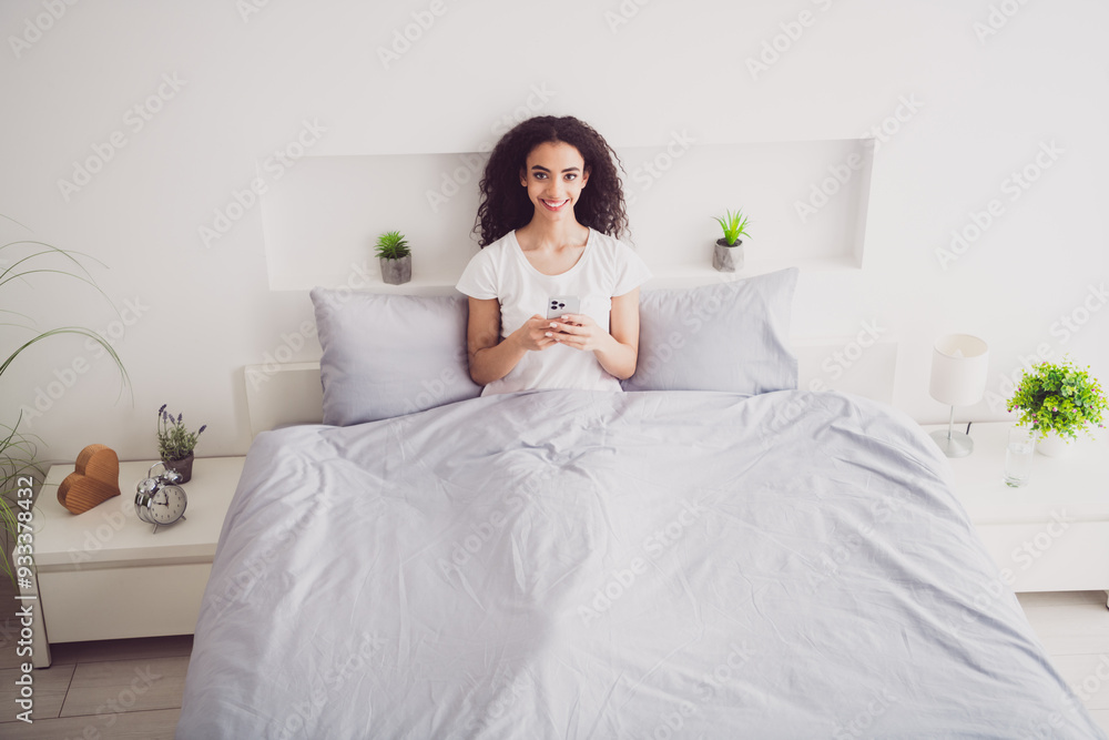 Photo of charming young woman lying bed hold device good morning vibes awake home bedroom light white interior Photo of charming young woman lying bed hold device good morning vibes awake home bedroom light white interior