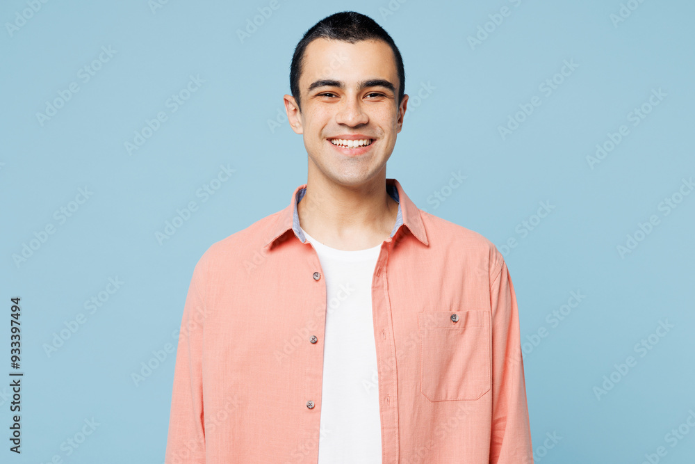 Young smiling happy cheerful fun satisfied cool middle eastern man wear pink shirt white t-shirt looking camera isolated on plain pastel light blue cyan background studio portrait. Lifestyle concept. Young smiling happy cheerful fun satisfied cool middle eastern man wear pink shirt white t-shirt looking camera isolated on plain pastel light blue cyan background studio portrait. Lifestyle concept.