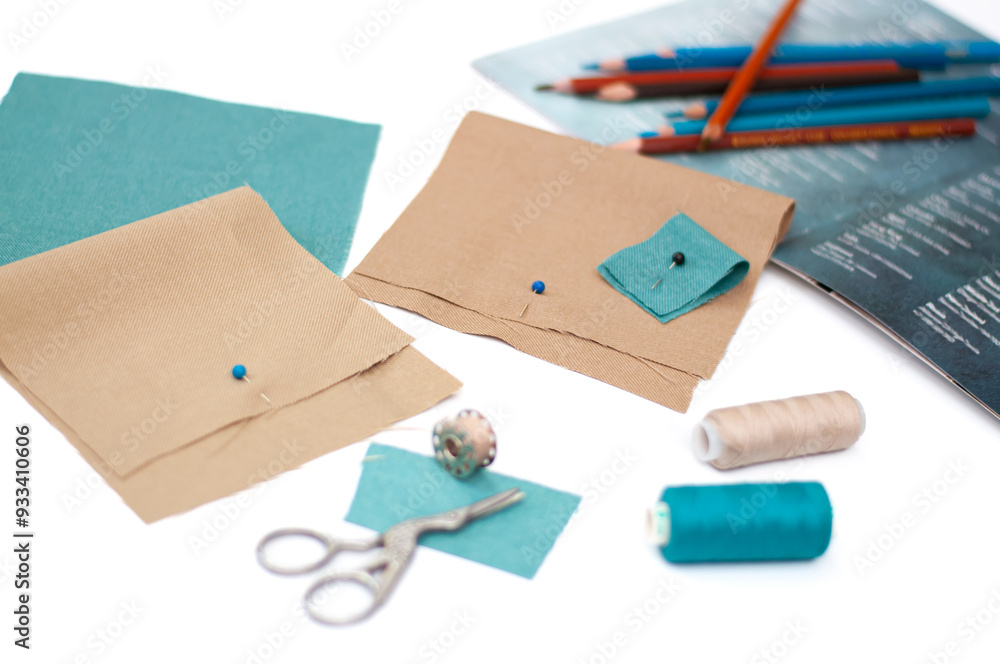 Samples of beige and turquoise fabric, scissors and coils with threads on a white background. Samples of beige and turquoise fabric, scissors and coils with threads on a white background.