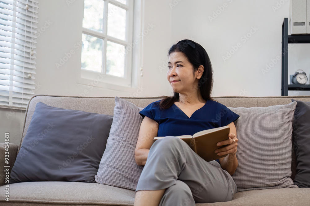 Elderly Woman Relaxing on Sofa at Home, Reading a Book, Enjoying Peaceful Afternoon in Cozy Living Room Elderly Woman Relaxing on Sofa at Home, Reading a Book, Enjoying Peaceful Afternoon in Cozy Living Room