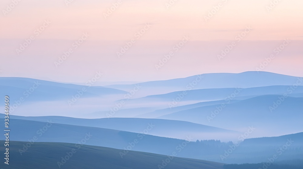 Obraz premium Rolling hills fading into the distance through layers of smoky haze with a soft pastel sky overhead