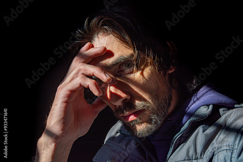 Rostro de hombre pensativo con mano sobre su frente en un fondo negro oscuro 