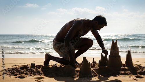 Silhouette of a man building a sandcastle on the beach photo