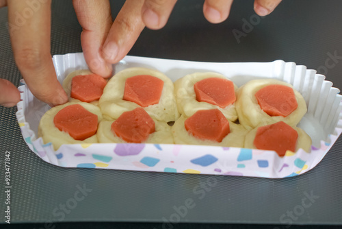 Sausage bun placed in a long paper baking cup.  Bread making process. Close up. photo