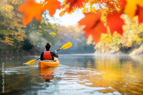 A kayaker enjoys a peaceful journey on calm waters, surrounded by vibrant fall leaves photo