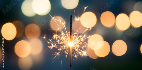 Glittering burning sparkler against blurred bokeh light background. New Year's Eve celebration