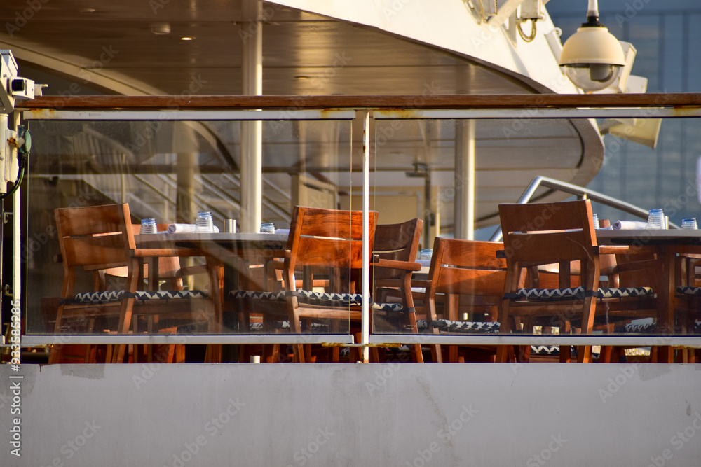 Obraz premium Outdoor seats on passenger ship deck with the calm seascape. Cruise ship deck. Wooden promenade deck on a luxury cruise liner. Ocean in background.
