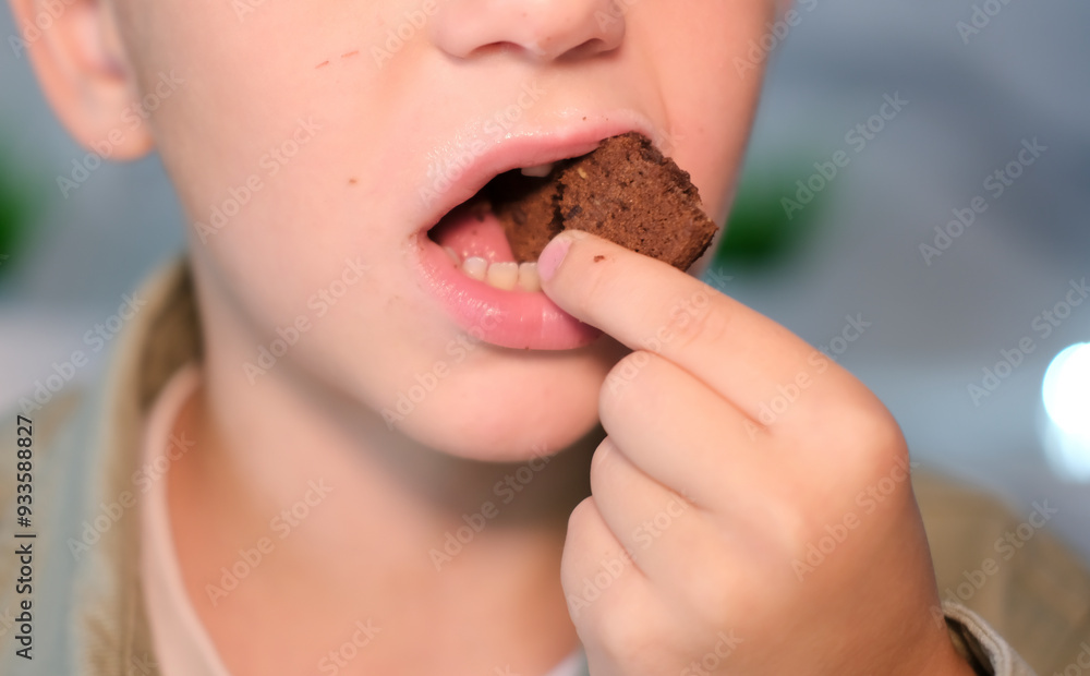 Boy eats chocolate chip cookies. Close-up of child eating cookie, biting cookie while sitting at dinner table. Sweet tooth. Boy eats chocolate chip cookies. Close-up of child eating cookie, biting cookie while sitting at dinner table. Sweet tooth.