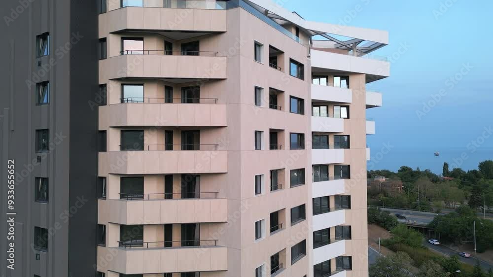 Aerial drone shot of a modern residential building facade with beige panels and white balconies, highlighting clean architectural lines and contemporary urban design Aerial drone shot of a modern residential building facade with beige panels and white balconies, highlighting clean architectural lines and contemporary urban design