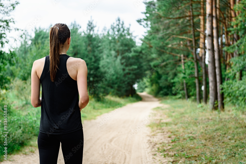 Young woman in black sportswear preparing for outdoor running in summer forest. Young woman in black sportswear preparing for outdoor running in summer forest.