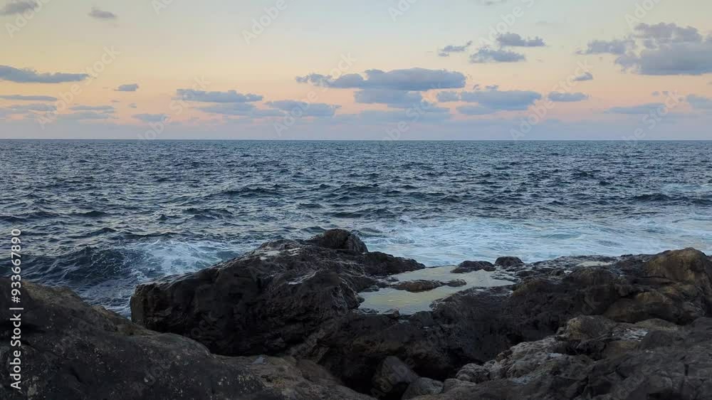 A panoramic view of towering rocky cliffs and the sea with waves crashing against the shore. A panoramic view of towering rocky cliffs and the sea with waves crashing against the shore.