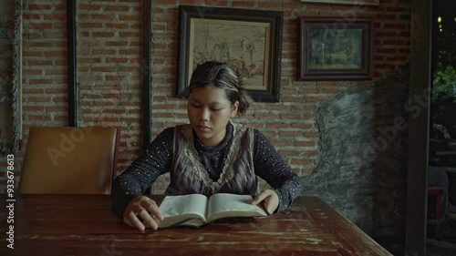 asian woman reading the bible book on wooden table vintage room