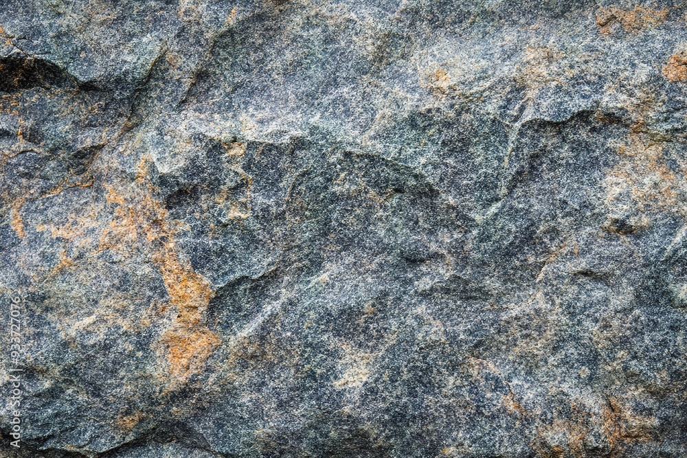 Rugged grey stone texture with patches of orange Rugged grey stone texture with patches of orange
