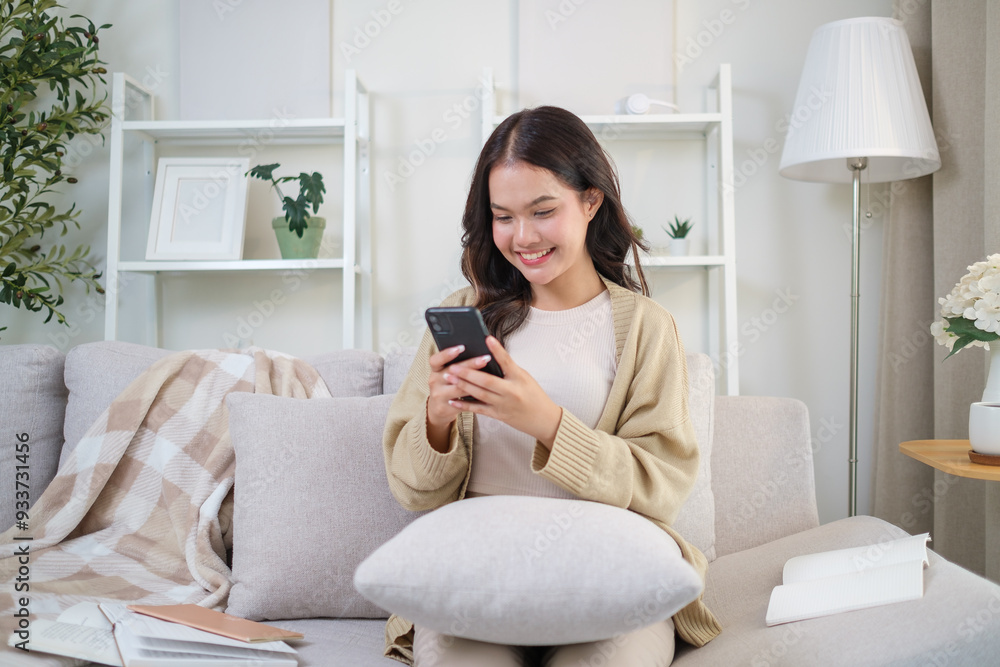 Happy young adult woman using mobile phone on sofa in cozy living room. Happy young adult woman using mobile phone on sofa in cozy living room.