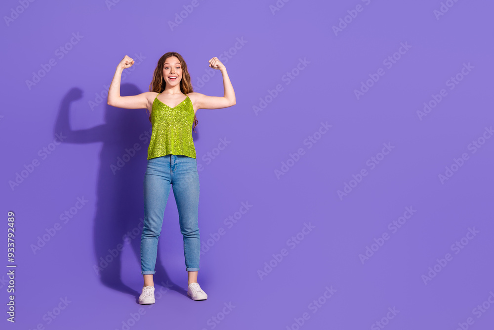 Full size photo of pretty teenager girl show muscles biceps wear trendy green outfit isolated on purple color background Full size photo of pretty teenager girl show muscles biceps wear trendy green outfit isolated on purple color background