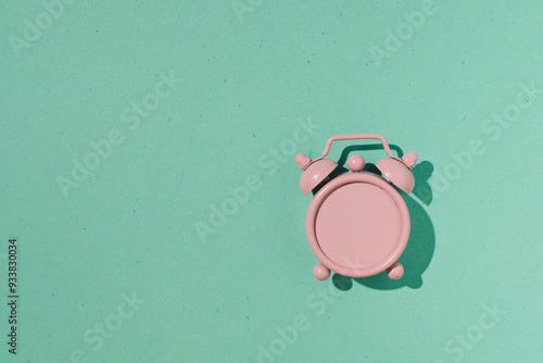 Analog alarm clock with empty clock face, pastel pink and moss green minimalist aesthetic composition.