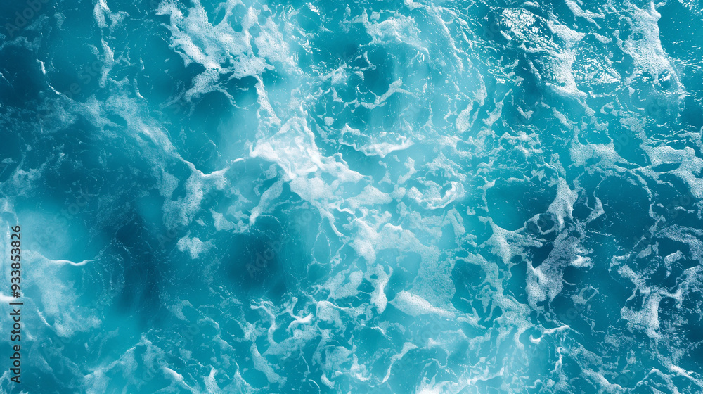 Obraz premium This image presents a stunning aerial view of ocean waves, showcasing the frothy white patterns against sparkling blue water, capturing the beauty and power of the sea in a remarkable visual.