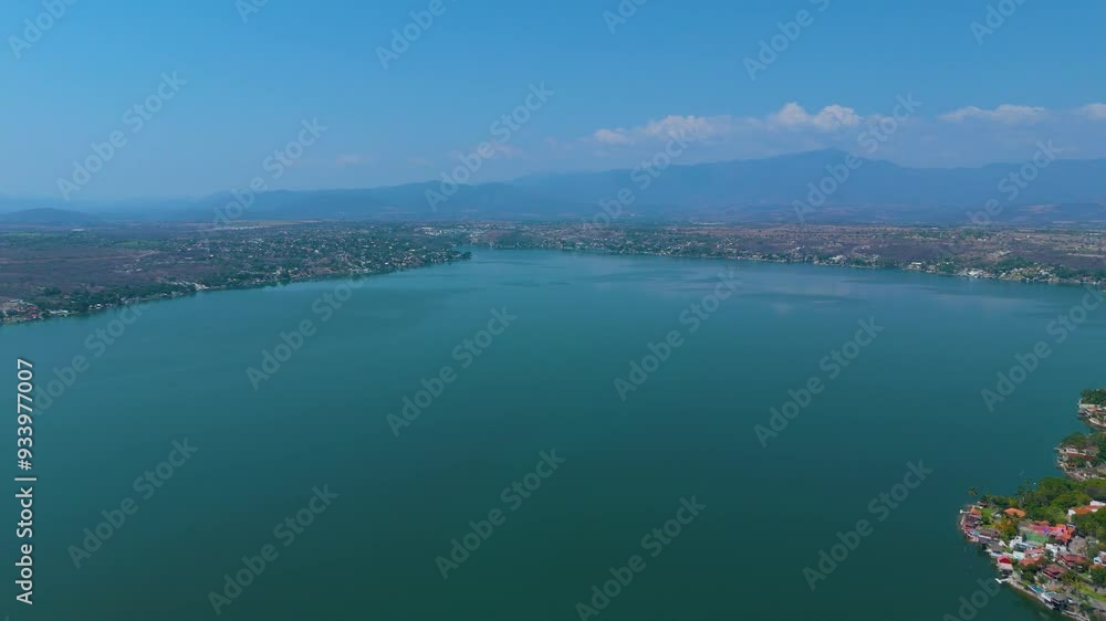 A gentle camera approach towards the serene Tequesquitengo Lake, an idyllic spot in the heart of Morelos, Mexico. The lake's tranquil waters mirror the blue sky, inviting us to relax and enjoy. A gentle camera approach towards the serene Tequesquitengo Lake, an idyllic spot in the heart of Morelos, Mexico. The lake's tranquil waters mirror the blue sky, inviting us to relax and enjoy.