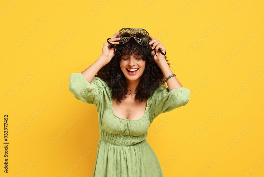 Smiling young woman with carnival mask on yellow background Smiling young woman with carnival mask on yellow background