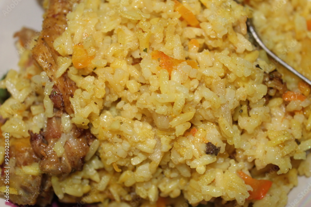 A colorful serving of yellow rice combined with fresh diced vegetables and succulent pieces of chicken is presented in a casual home kitchen, capturing a comforting midday meal A colorful serving of yellow rice combined with fresh diced vegetables and succulent pieces of chicken is presented in a casual home kitchen, capturing a comforting midday meal