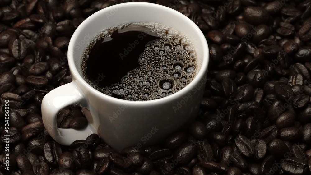 Fototapeta premium Top view of coffee or espresso with piles of coffee beans. Close up of fresh roasted coffee bean scatter around wooden table with cup of americano and aromatic stream and smoke from seed. Comestible.