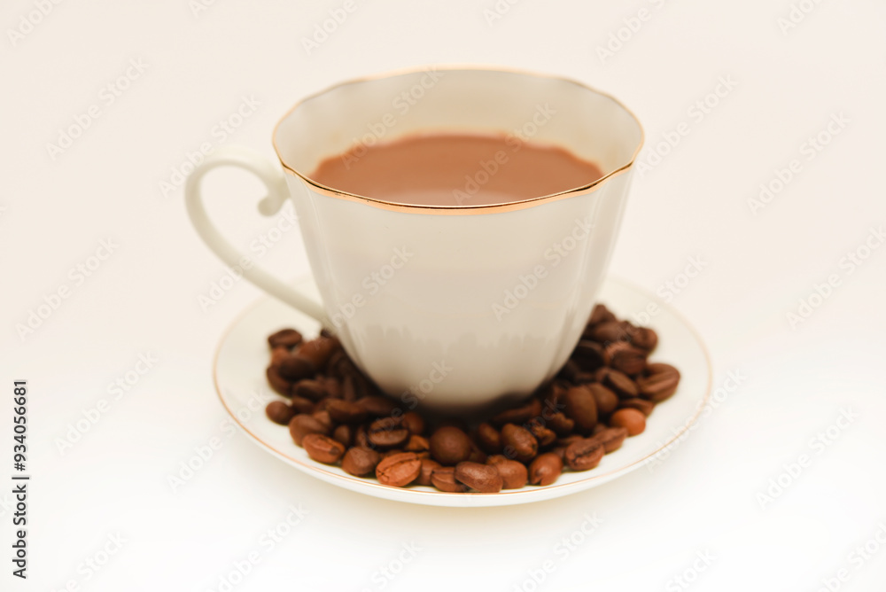 A white cup of coffee and scattered coffee beans. A white cup of coffee and scattered coffee beans.