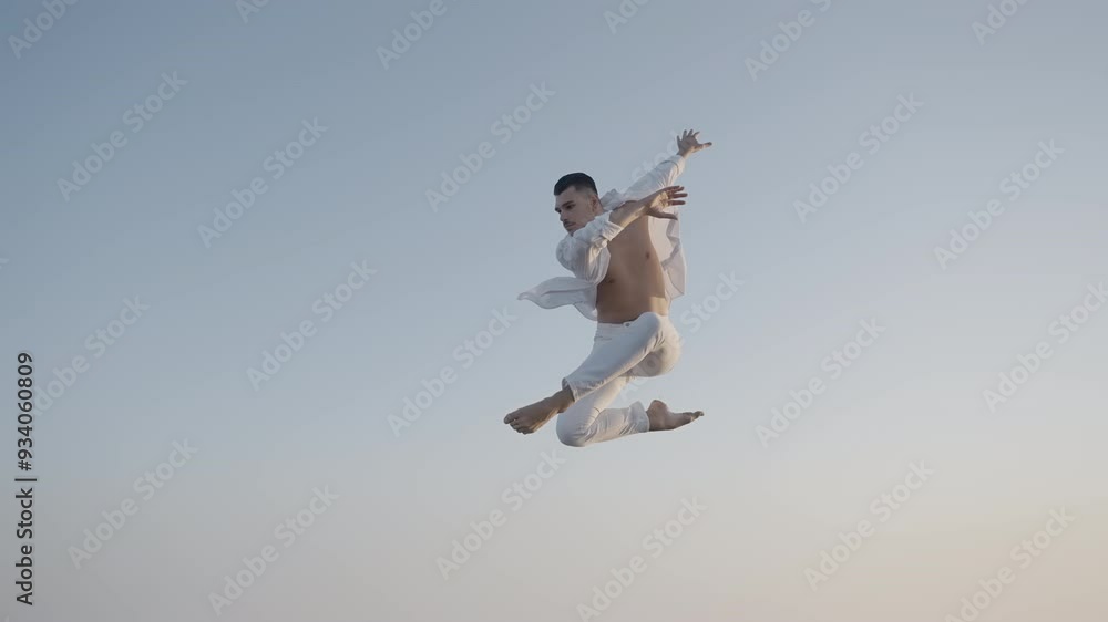 A dynamic dance leap performed gracefully against a clear sky A dynamic dance leap performed gracefully against a clear sky