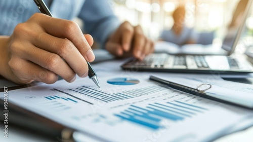 Accountant's hands working with a ledger and a set of financial documents on a desk.