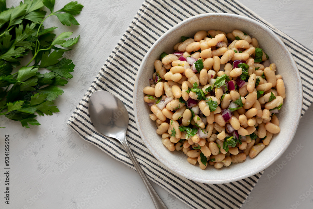 Homemade White Bean Salad with Herbs and Onion in a Bowl, top view. Flat lay, overhead, from above.