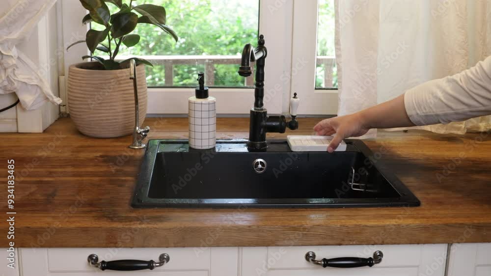 a housewife puts kitchen utensils and dishes near the sink a housewife puts kitchen utensils and dishes near the sink