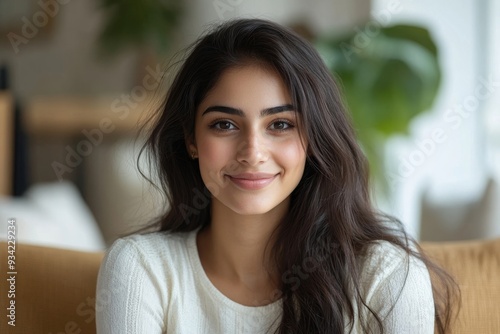 Head shot portrait smiling attractive Indian woman making video call, sitting on couch at home, happy young female chatting online with friends or relatives, internet meeting, blogger, Generative AI