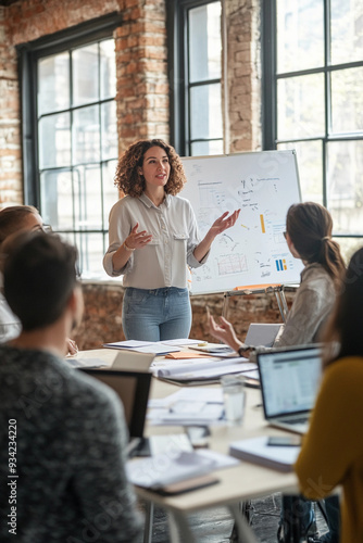 Female entrepreneur leading a team in a tech startup – A dynamic, diverse group of professionals gathered around a table with laptops and tablets