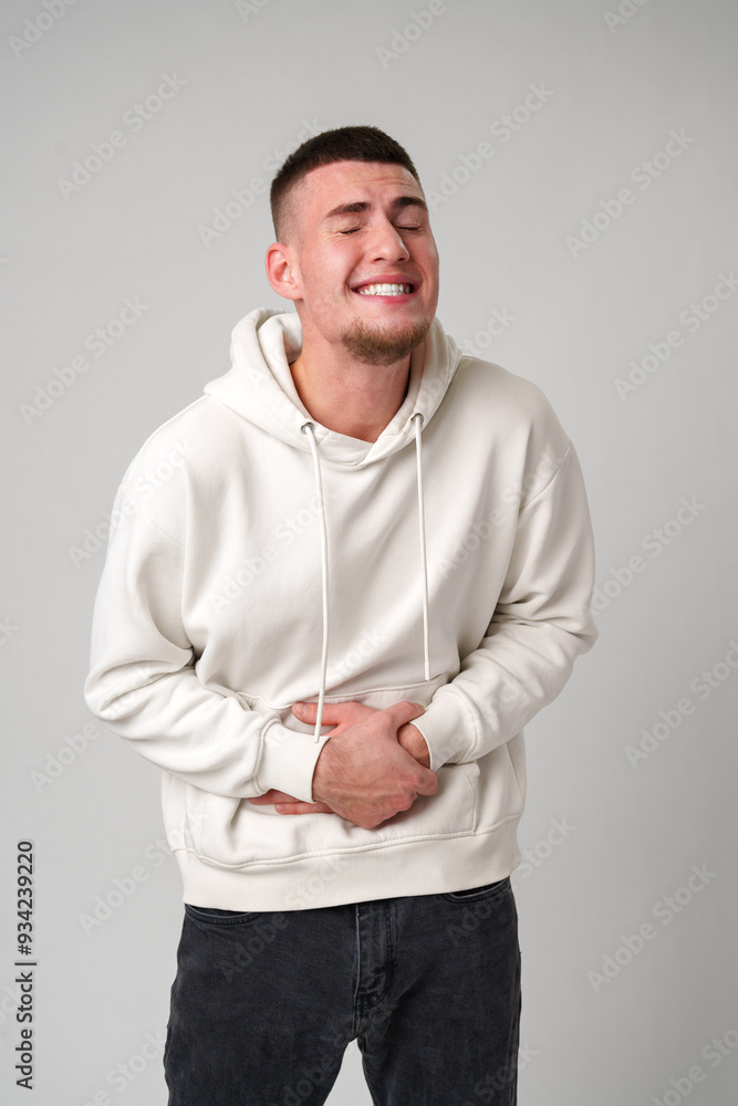 Young Man in White Hoodie Experiencing Stomach Pain Young Man in White Hoodie Experiencing Stomach Pain