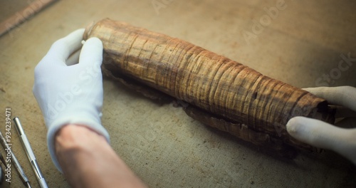 Scientists study cultural heritage of extinct human civilization. Two archaeologists in gloves carefully unroll ancient Egyptian papyrus on table in archaeological laboratory and talk. Archaeology.