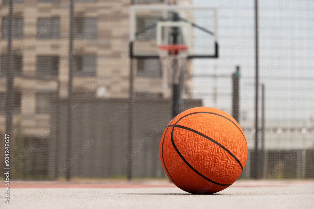 Naklejka premium Basketball orange ball lying on court floor, outdoor public park at city. Basketball at courtyard. Sports gear without people. Template, sport background. Copy space. Close up.