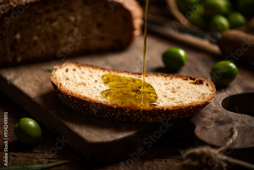 Fototapeta Naklejka Na Ścianę i Meble -  Pouring oil onto slice of bread on wooden board