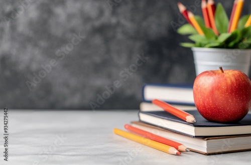 Fresh red apple sits on stacked notebooks in a classroom with colorful pencil...
