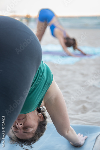 a group of two people practicing yoga in a downward facing dog pose photo