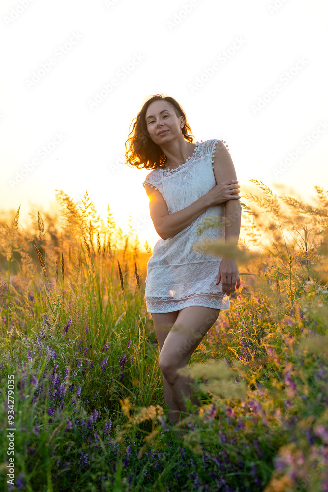 Young sexy woman in a white mini dress in a field at sunset. Photo session in nature. Young sexy woman in a white mini dress in a field at sunset. Photo session in nature.