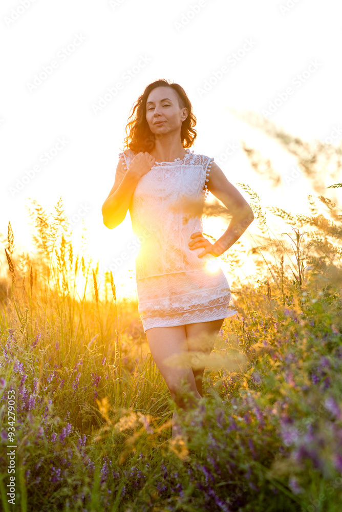 Young sexy woman in a white mini dress in a field at sunset. Photo session in nature. Young sexy woman in a white mini dress in a field at sunset. Photo session in nature.