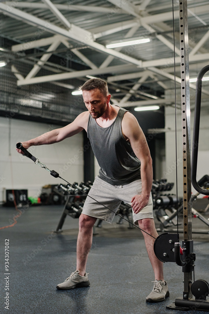 Caucasian man testing new shoulder exercise in functional trainer, he focused on excellent technique Caucasian man testing new shoulder exercise in functional trainer, he focused on excellent technique