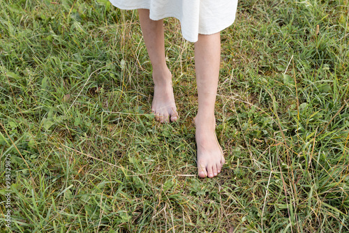 Girl walking barefoot on green grass, closeup photo