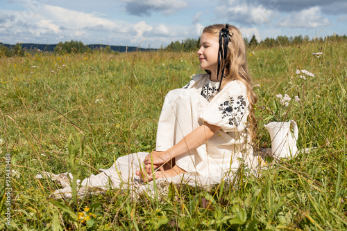 preschool girl sitting on the grass and looking into the distance