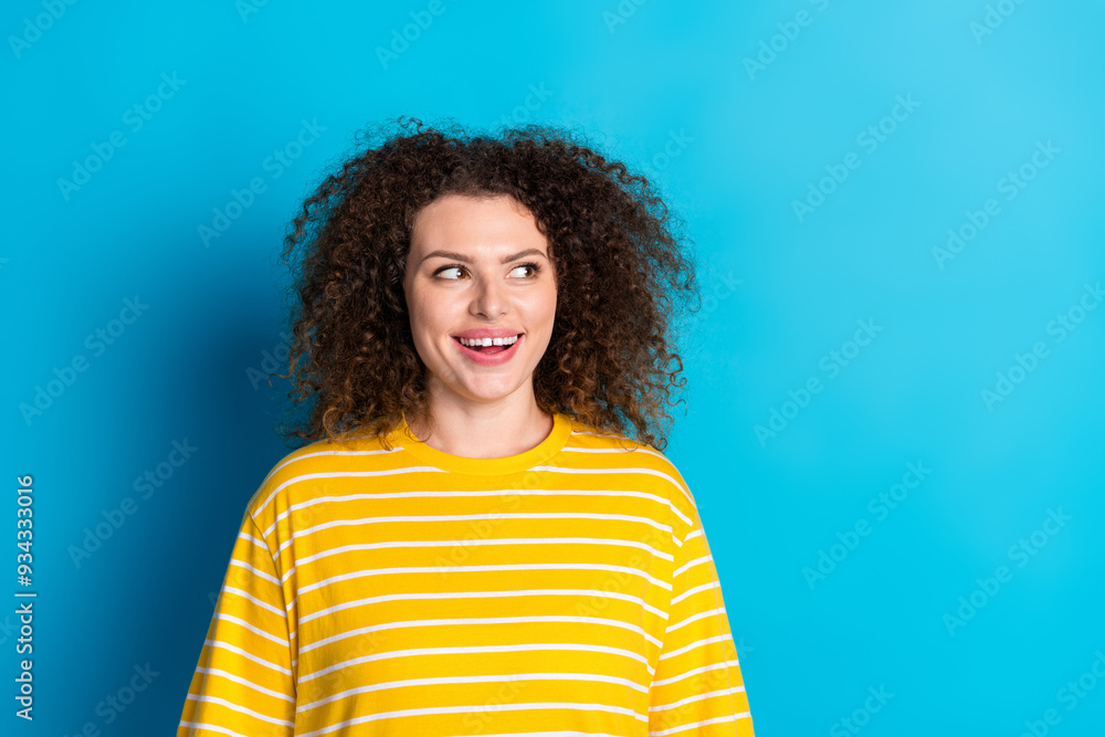 Photo portrait of pretty young girl look empty space wear trendy striped yellow outfit isolated on blue color background Photo portrait of pretty young girl look empty space wear trendy striped yellow outfit isolated on blue color background