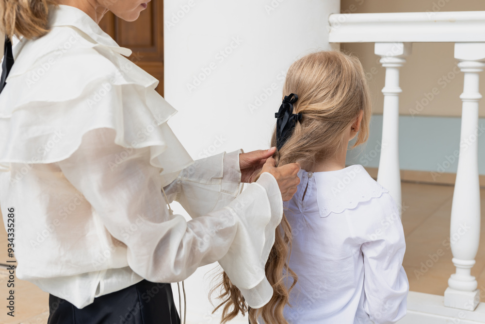 Fototapeta premium Mom makes her daughter's hair on street