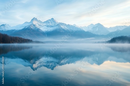 A tranquil mountain lake glows with the first light of dawn, enveloped in mist, while snowcapped peaks provide a stunning backdrop reflected in the still waters