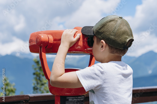 boy observing mountains panorama through stationary binoculars photo