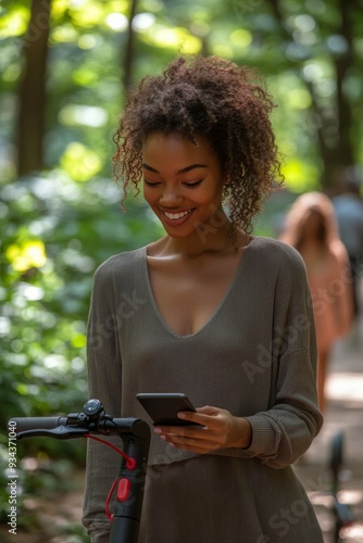 Young woman smiling while using her smartphone in a sunlit park